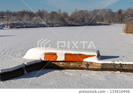 There is an overturned boat covered in snow lying on the pier. 135610498