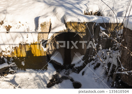 A snow-covered concrete drain pipe on a clear winter day A snow-covered concrete drain pipe on a clear winter day 135610504