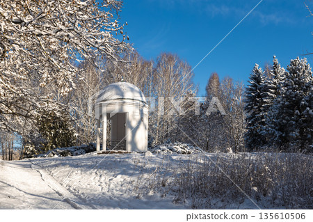 A snow-covered gazebo in a beautiful winter park on a clear day 135610506