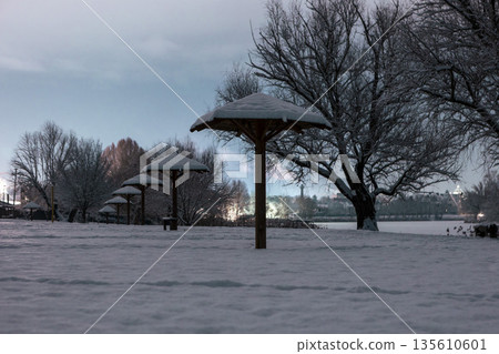 Umbrella-shaped canopies on a snowy winter night beach Umbrella-shaped canopies on a snowy winter night beach 135610601