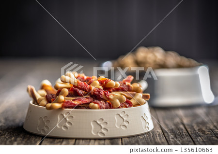 Dog food. Snack sticks for dogs in bowl on wooden table. 135610663