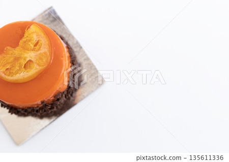 Round orange chocolate pastry decorated with an orange slice, elegant modern dessert 135611336