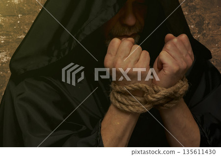 Bound monk hands holding rosary on dark background 135611430