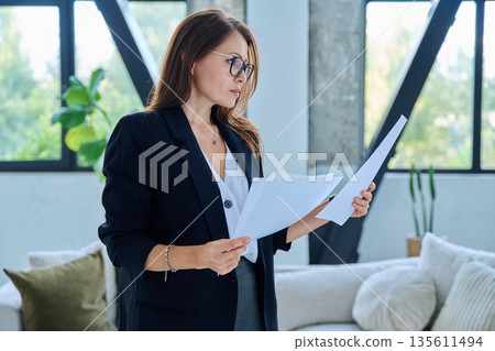 Portrait of middle-aged confident businesswoman with business papers 135611494