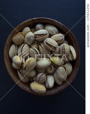 Pistachios in Wooden Bowl on Dark Background Pistachios in Wooden Bowl on Dark Background 135612292