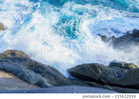 Rough waves crashing against the rocks, white spray and the dynamic energy of the ocean Rough waves crashing against the rocks, white spray and the dynamic energy of the ocean 135612839