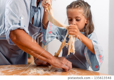 Grandmother and granddaughter making dough Grandmother and granddaughter making dough 135613548