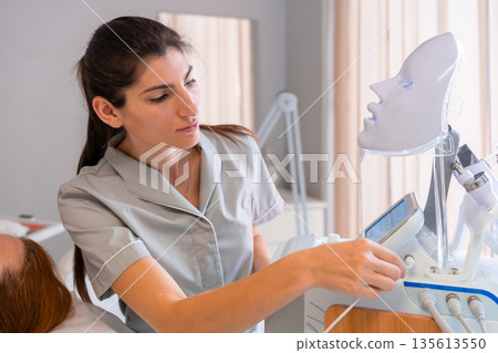 Cosmetologist preparing LED light therapy mask Cosmetologist preparing LED light therapy mask 135613550