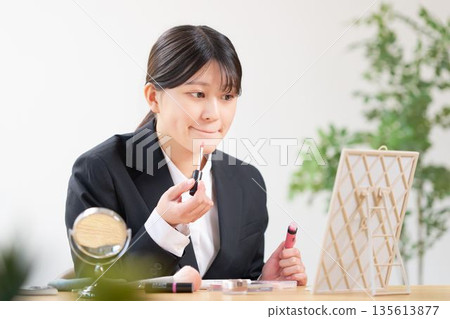 一位身穿招生職業裝的女學生正在鏡子前補妝。 一位身穿招生職業裝的女學生正在鏡子前補妝。 135613877