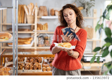 Woman capturing a sandwich photo in a bakery Woman capturing a sandwich photo in a bakery 135613972