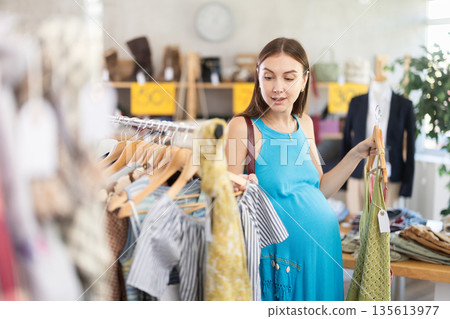 Pregnant woman choosing clothes Pregnant woman choosing clothes 135613977