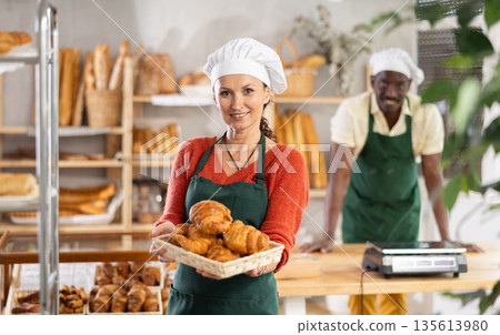Portrait of joyful woman baker with croissants 135613980