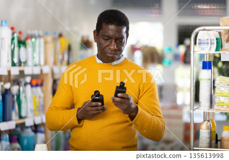 African man sniffs fragrance of perfume, chooses scent spray with pleasant smell African man sniffs fragrance of perfume, chooses scent spray with pleasant smell 135613998