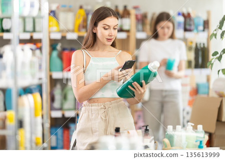 Woman scanning a package of detergent on her phone Woman scanning a package of detergent on her phone 135613999