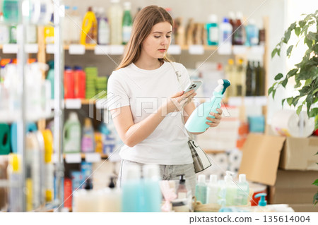 Young woman scanning qr code for cleaning spray Young woman scanning qr code for cleaning spray 135614004