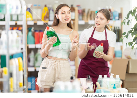 Sales girl offers woman choose dishwashing in household supermarket 135614031