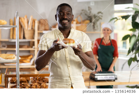 Portrait of male customer with tasty bocadillo in bakery Portrait of male customer with tasty bocadillo in bakery 135614036