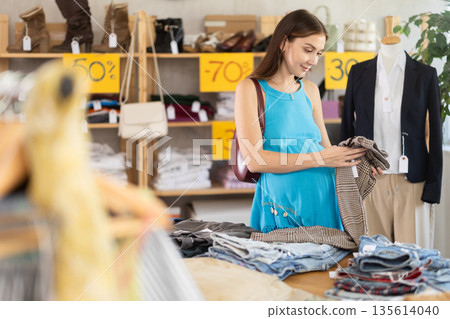 pregnant woman chooses pants in a store pregnant woman chooses pants in a store 135614040