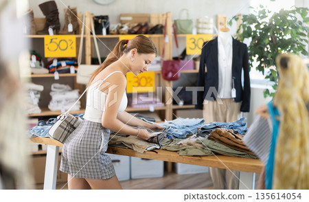 Young woman choosing pants during seasonal sale Young woman choosing pants during seasonal sale 135614054