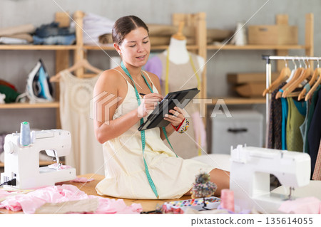 Woman dressmaker drawing on tablet Woman dressmaker drawing on tablet 135614055