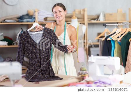 dressmaker presents a ready-made dress in a workshop dressmaker presents a ready-made dress in a workshop 135614071