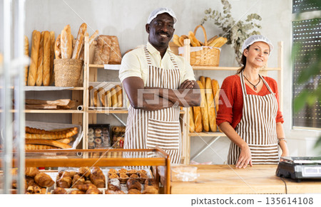 Portrait of two bakery employees - man and woman showing delicious baguettes and croissants Portrait of two bakery employees - man and woman showing delicious baguettes and croissants 135614108