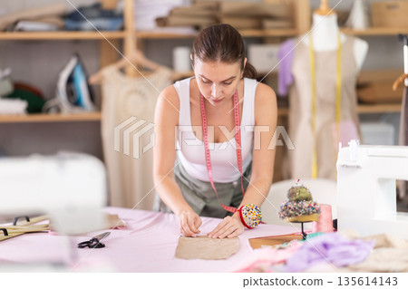 Woman seamstress works with pattern and fabric 135614143