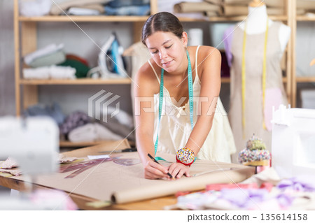 Woman dressmaker draws patterns using curved rulers Woman dressmaker draws patterns using curved rulers 135614158