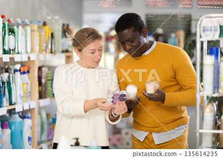 Couple man and woman choosing scented candles in store 135614235
