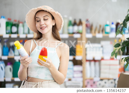 Woman in a hat holding a repellent in her hands in a supermarket 135614237