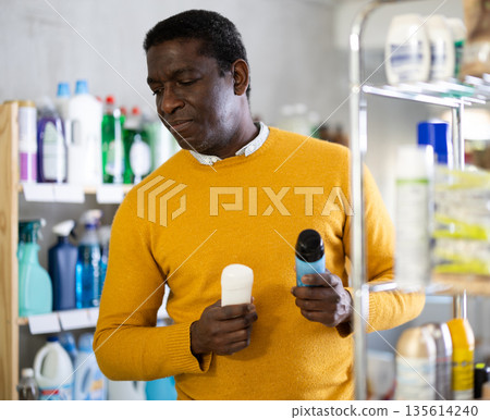 Before buying in household shop, African male customer choose roll on deodorant Before buying in household shop, African male customer choose roll on deodorant 135614240