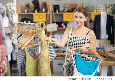 Female shopper looking for summer clothing in outlet store 135614264