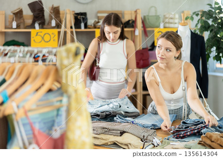 Female shoppers looking for shorts and pants in clothing store Female shoppers looking for shorts and pants in clothing store 135614304