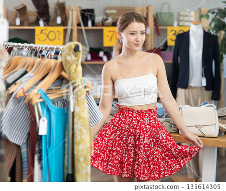 Young woman trying on a red skirt Young woman trying on a red skirt 135614305