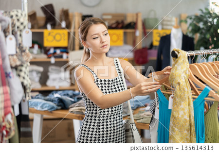 Young woman shopping for summer outfits in store Young woman shopping for summer outfits in store 135614313