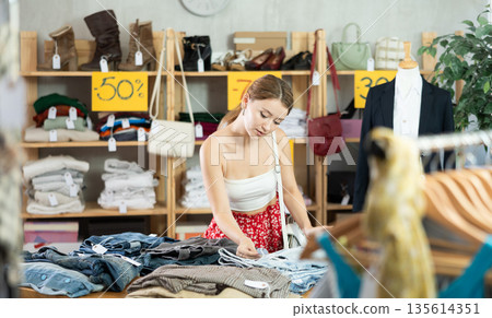 European woman choosing pants in a clothing store European woman choosing pants in a clothing store 135614351