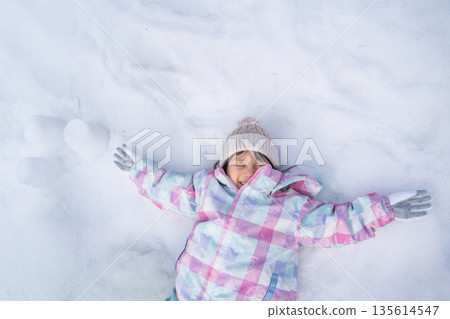 Child sleeping on the snow with arms outstretched 135614547