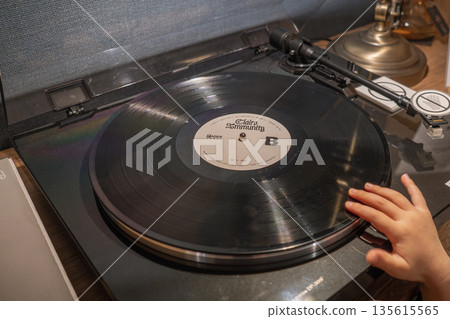 A child putting a record on a record player A child putting a record on a record player 135615565
