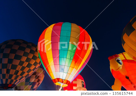 colorful hot air balloons glowing against dark night sky 135615744