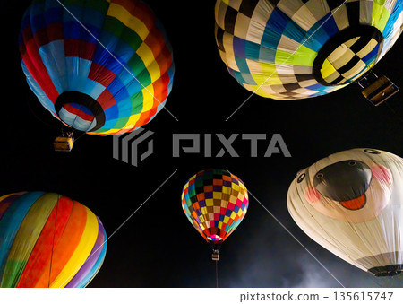 colorful hot air balloons glowing against dark night sky 135615747