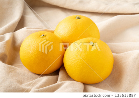 三個八朔橘子放在一塊布上。 135615887