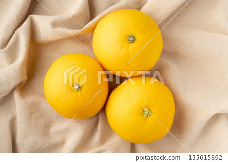 Three hassaku oranges placed on a cloth 135615892