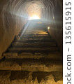 Stone stairs in a tunnel with light streaming in 135615915