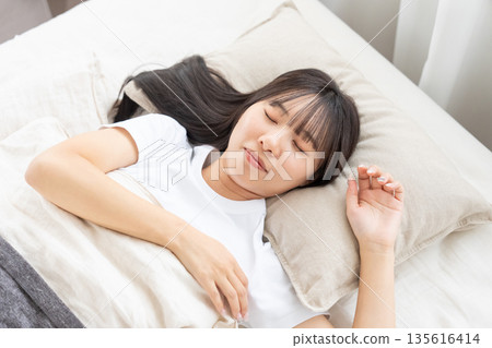 一個睡在床上的年輕女人 135616414