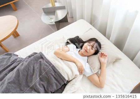 一個睡在床上的年輕女人 135616415