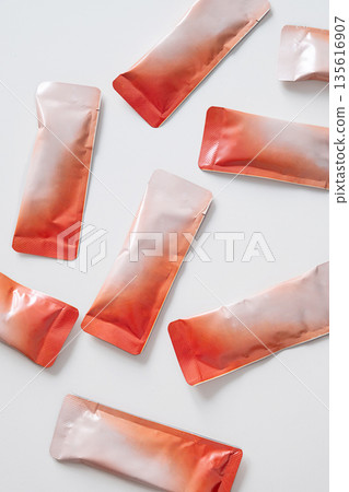 Many small red and white sealed plastic sachets with powder. Many small red and white sealed plastic sachets with powder. 135616907