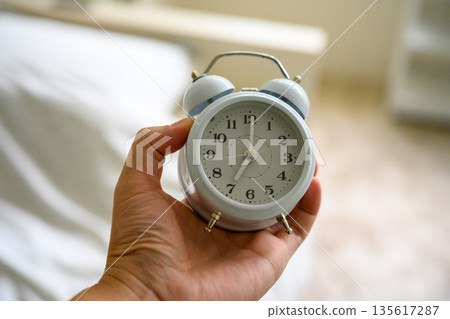 holding an alarm clock holding an alarm clock 135617287