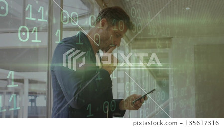 Standing executive holding smartphone and thinking in glass office corridor, with binary code 135617316