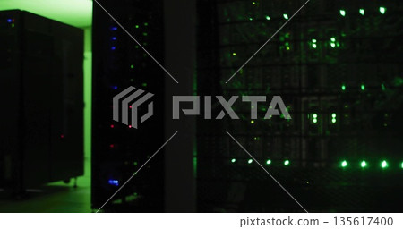 Rack-mounted servers pulsing LED lights in server room corridor, with switches and patch cables 135617400