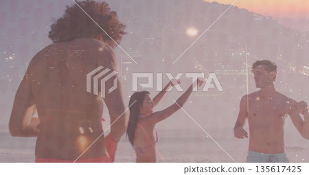 Standing three friends wearing bikini, trunks in water on sunset beach, with paddle skyline overlay 135617425